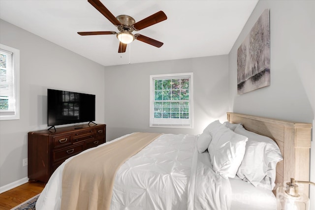 bedroom with a ceiling fan, baseboards, and wood finished floors