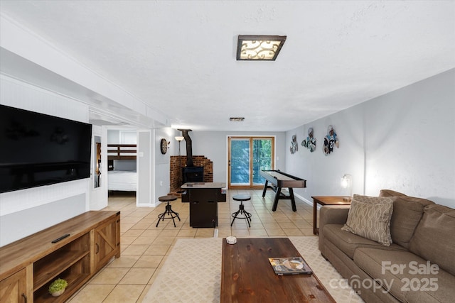 living room with a wood stove, light tile patterned floors, and baseboards