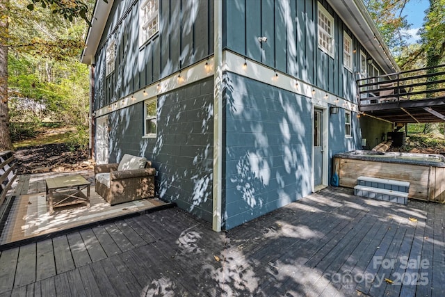 view of side of property with concrete block siding, a hot tub, and a deck