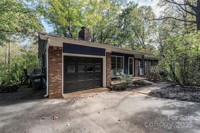 ranch-style home featuring an attached garage, driveway, a chimney, and brick siding