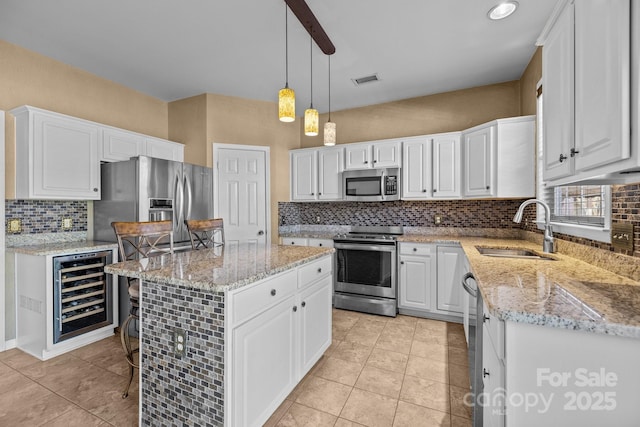 kitchen with stainless steel appliances, beverage cooler, white cabinets, and a sink