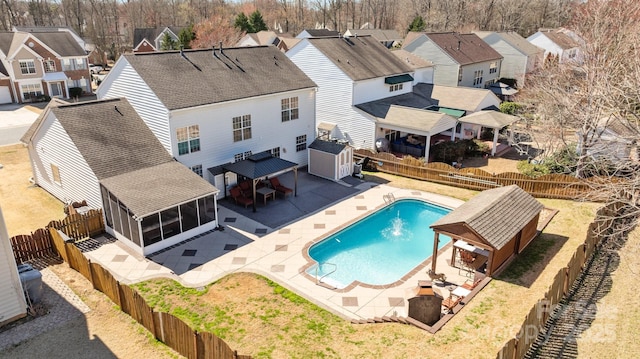 view of pool with a residential view, a sunroom, a fenced backyard, and a patio