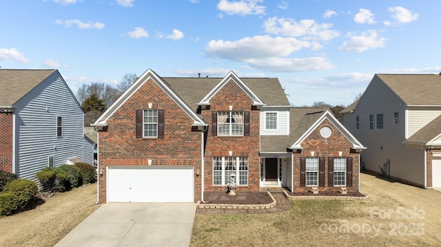 traditional-style house featuring driveway, an attached garage, a front yard, and brick siding