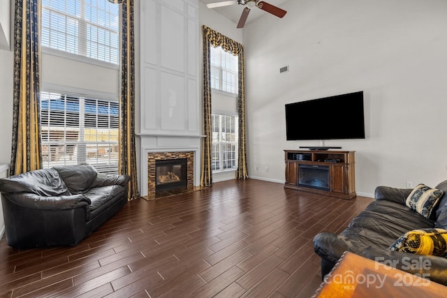 living area featuring dark wood-type flooring, a fireplace with flush hearth, and a high ceiling