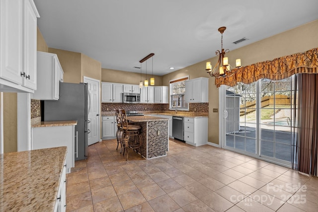 kitchen with a wealth of natural light, appliances with stainless steel finishes, visible vents, and tasteful backsplash