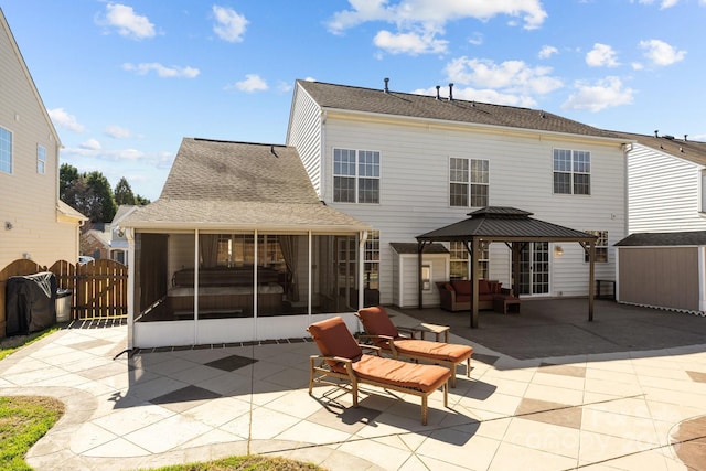 rear view of property featuring a sunroom, roof with shingles, a gate, a gazebo, and a patio area