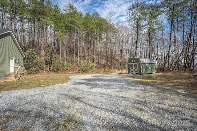 view of street featuring entry steps, driveway, and a wooded view