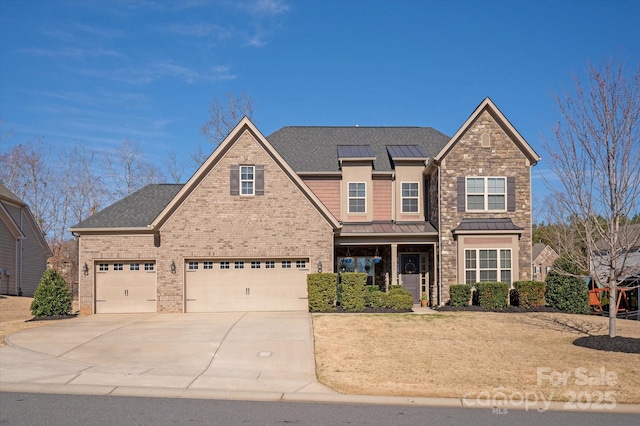 view of front of property featuring metal roof, a garage, brick siding, driveway, and a standing seam roof