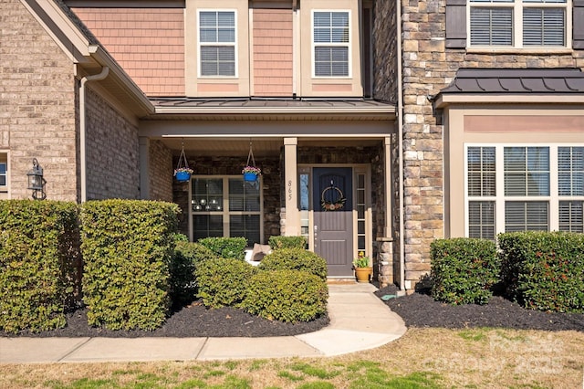 view of exterior entry featuring stone siding, a standing seam roof, and metal roof