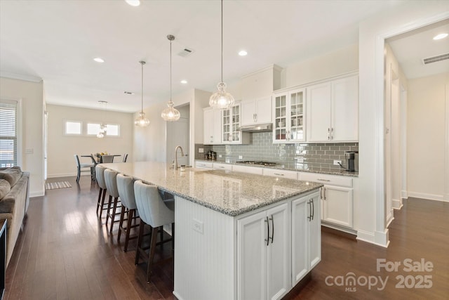 kitchen featuring dark wood-type flooring, visible vents, stainless steel gas cooktop, and white cabinetry