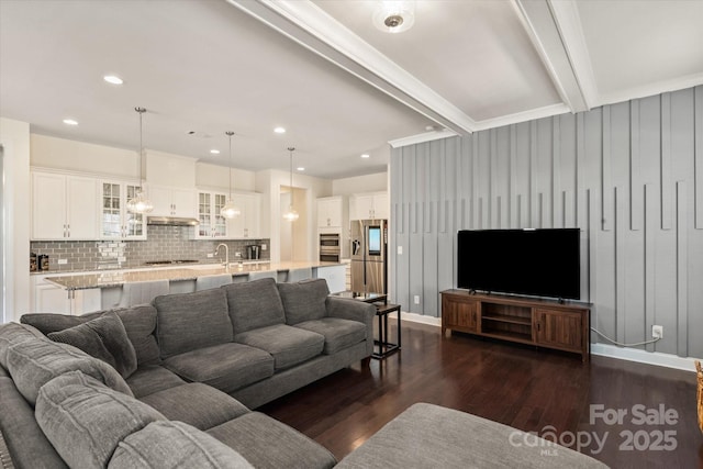 living room featuring dark wood-style floors, recessed lighting, beam ceiling, and baseboards