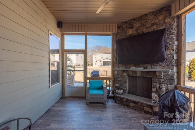 sunroom / solarium featuring wooden ceiling and an outdoor stone fireplace