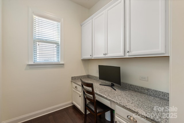 office area with dark wood-style floors, baseboards, and built in desk