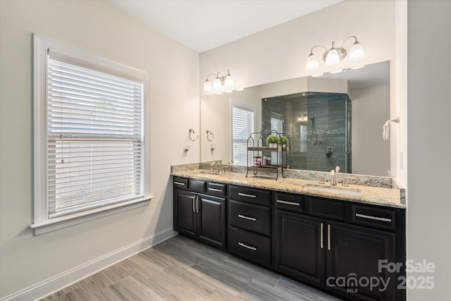 bathroom featuring baseboards, double vanity, a sink, and a shower stall