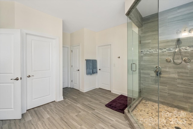 bathroom with a stall shower, baseboards, and wood finished floors