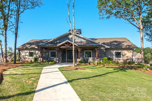 craftsman-style house with stone siding, a standing seam roof, and a front yard