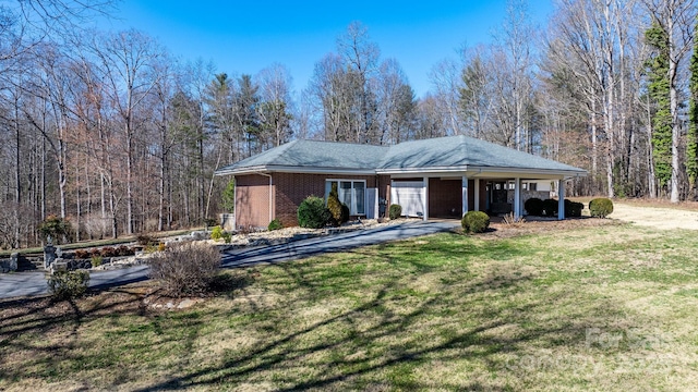 view of front of house with a carport, brick siding, a front yard, and a wooded view