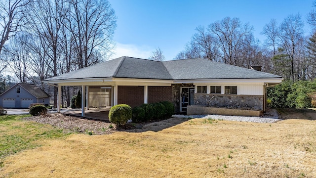 view of front of house with stone siding, roof with shingles, and a front yard