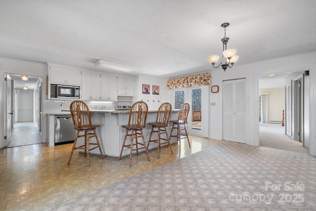 kitchen with black microwave, stone counters, white cabinetry, dishwasher, and pendant lighting