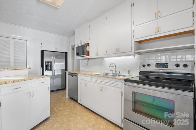 kitchen with white cabinets, decorative backsplash, stainless steel appliances, light floors, and a sink