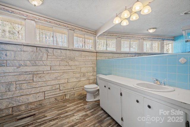 bathroom with toilet, plenty of natural light, a textured ceiling, and wood finished floors