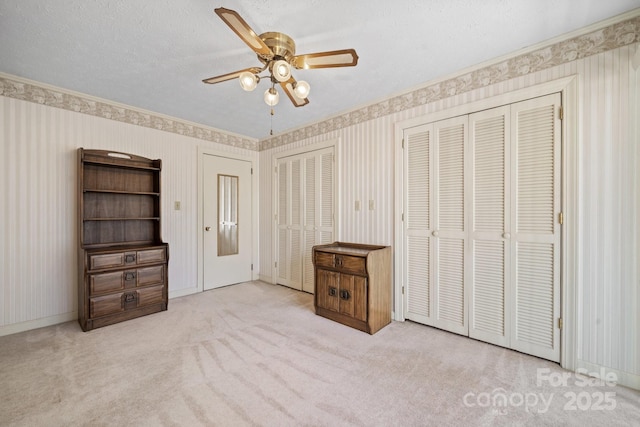 unfurnished bedroom with light colored carpet, crown molding, a textured ceiling, and wallpapered walls