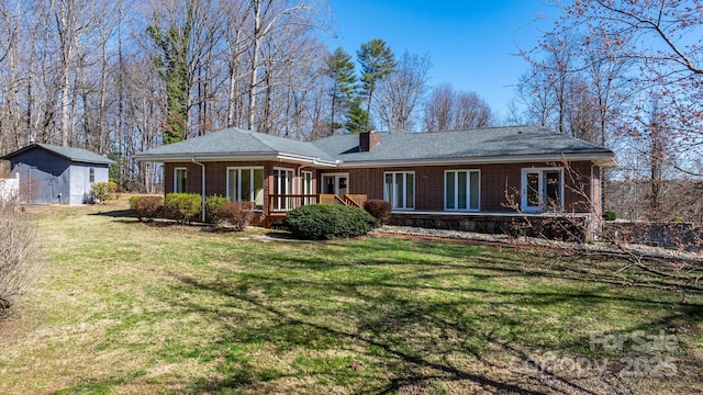 rear view of house featuring an outbuilding, brick siding, a lawn, and a storage unit