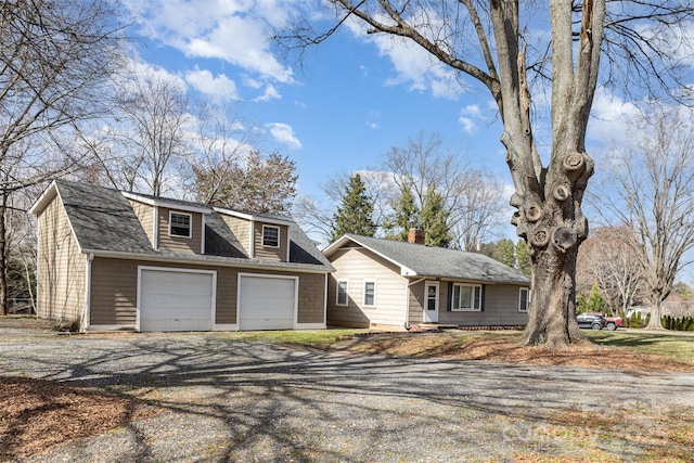 view of front facade with a garage, roof with shingles, and gravel driveway