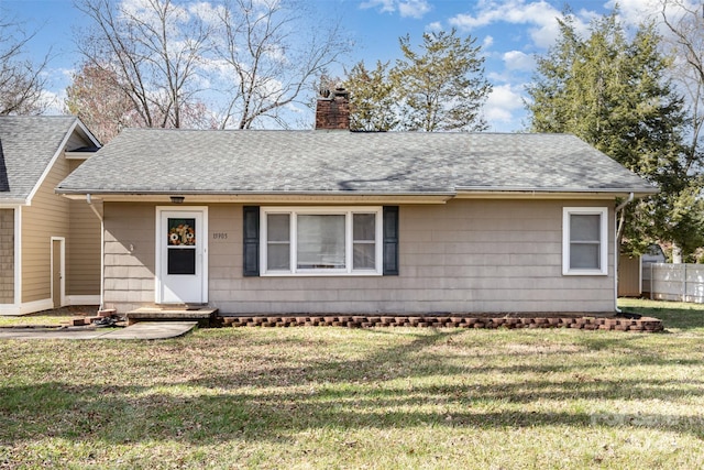 view of front of property featuring roof with shingles, fence, a chimney, and a front lawn