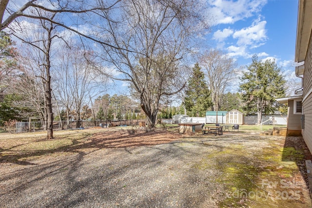 view of yard featuring a shed, fence, and an outdoor structure