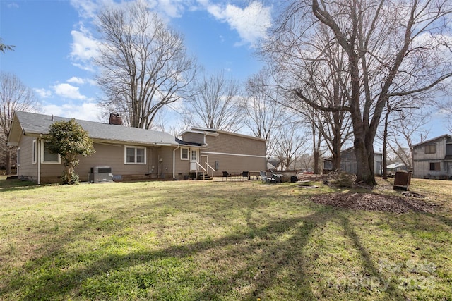 rear view of house with entry steps, crawl space, a chimney, and a lawn