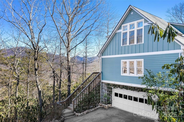 view of home's exterior with stairs, aphalt driveway, board and batten siding, and an attached garage