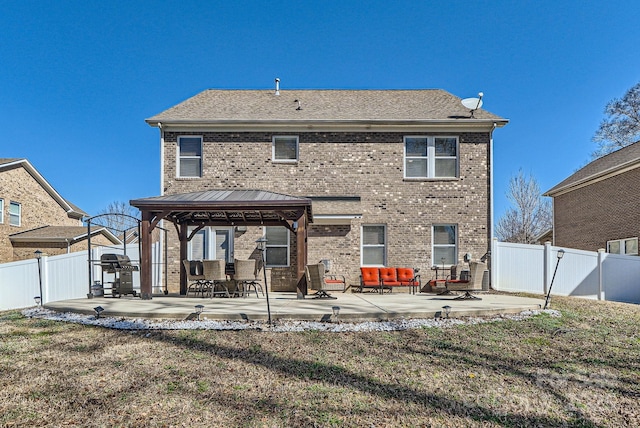 rear view of house with a patio area, a fenced backyard, brick siding, and a gazebo