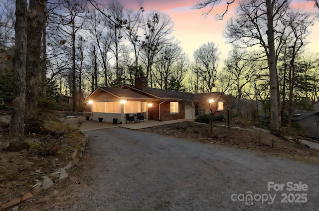 ranch-style home with brick siding, driveway, and a chimney