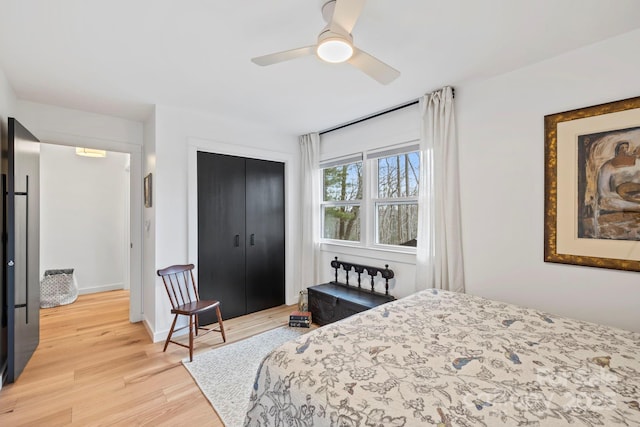 bedroom with light wood-type flooring, a closet, ceiling fan, and baseboards