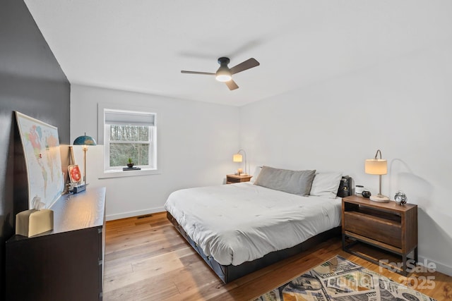 bedroom featuring visible vents, baseboards, ceiling fan, and wood finished floors