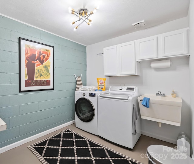 washroom with concrete block wall, cabinet space, visible vents, a sink, and washer and dryer