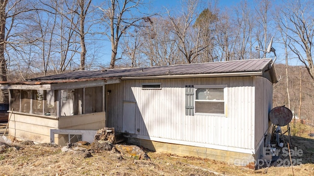 view of side of property featuring a sunroom and metal roof