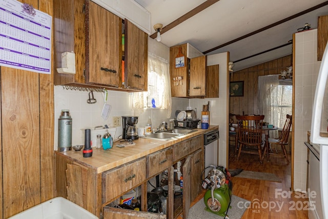 kitchen featuring lofted ceiling, brown cabinetry, a sink, and decorative backsplash