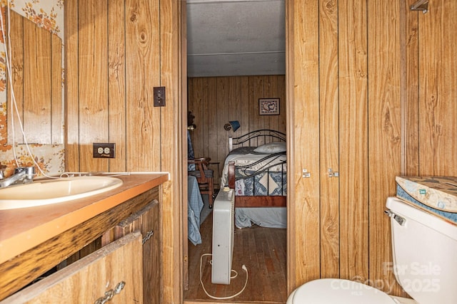 half bathroom with wood walls, vanity, and toilet