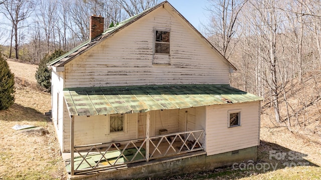 exterior space with crawl space, metal roof, and a chimney