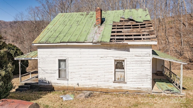 view of side of home featuring a standing seam roof, a chimney, and metal roof