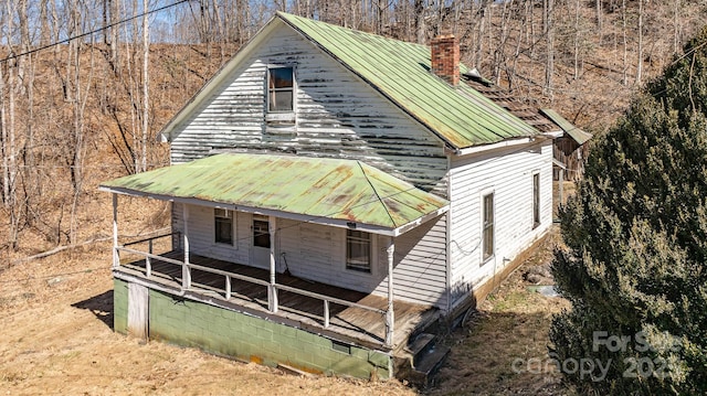 exterior space featuring covered porch, metal roof, and a chimney