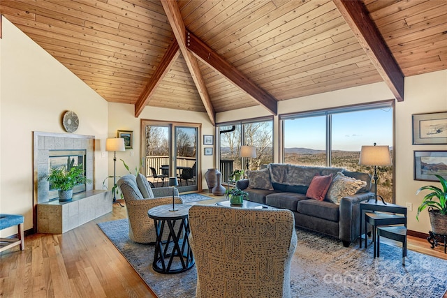 living area featuring a tiled fireplace, plenty of natural light, and wood finished floors