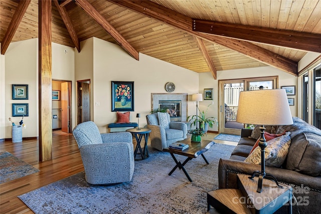 living room featuring a glass covered fireplace, wood ceiling, wood finished floors, and baseboards