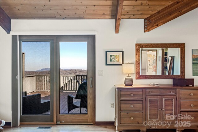 entryway featuring visible vents, baseboards, light wood-style flooring, vaulted ceiling with beams, and wood ceiling