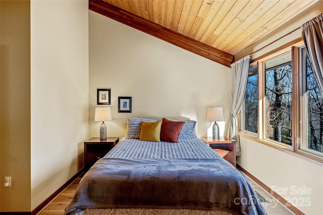 bedroom with wooden ceiling, vaulted ceiling with beams, wood finished floors, and baseboards