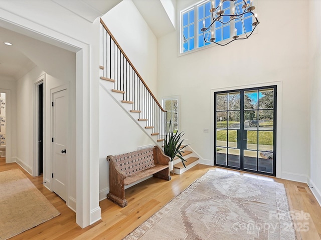 foyer entrance featuring baseboards, a notable chandelier, stairway, and wood finished floors