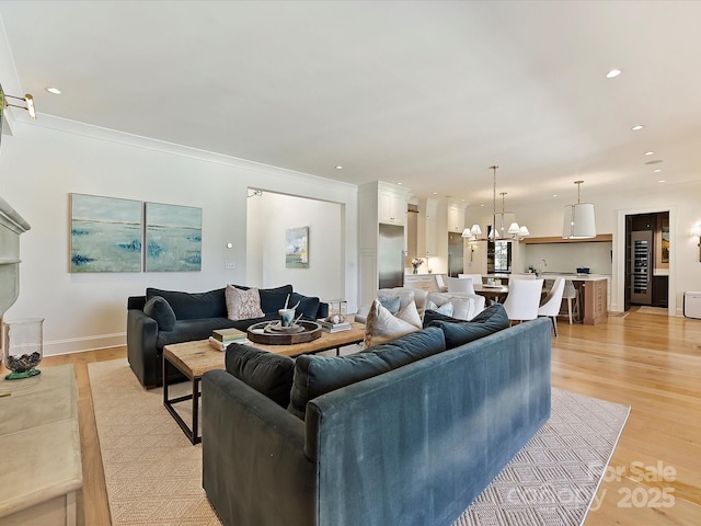 living area featuring recessed lighting, light wood-style flooring, baseboards, and an inviting chandelier