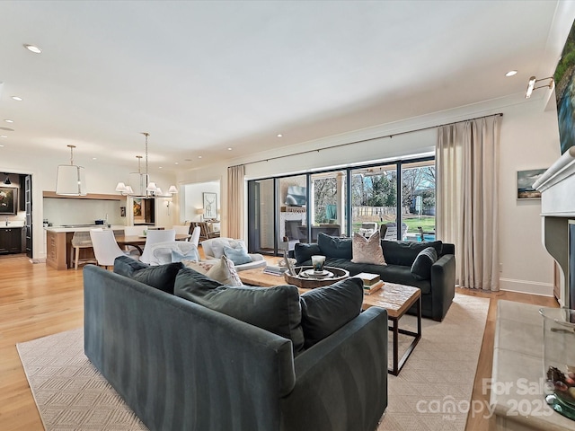 living area featuring baseboards, light wood-type flooring, and recessed lighting